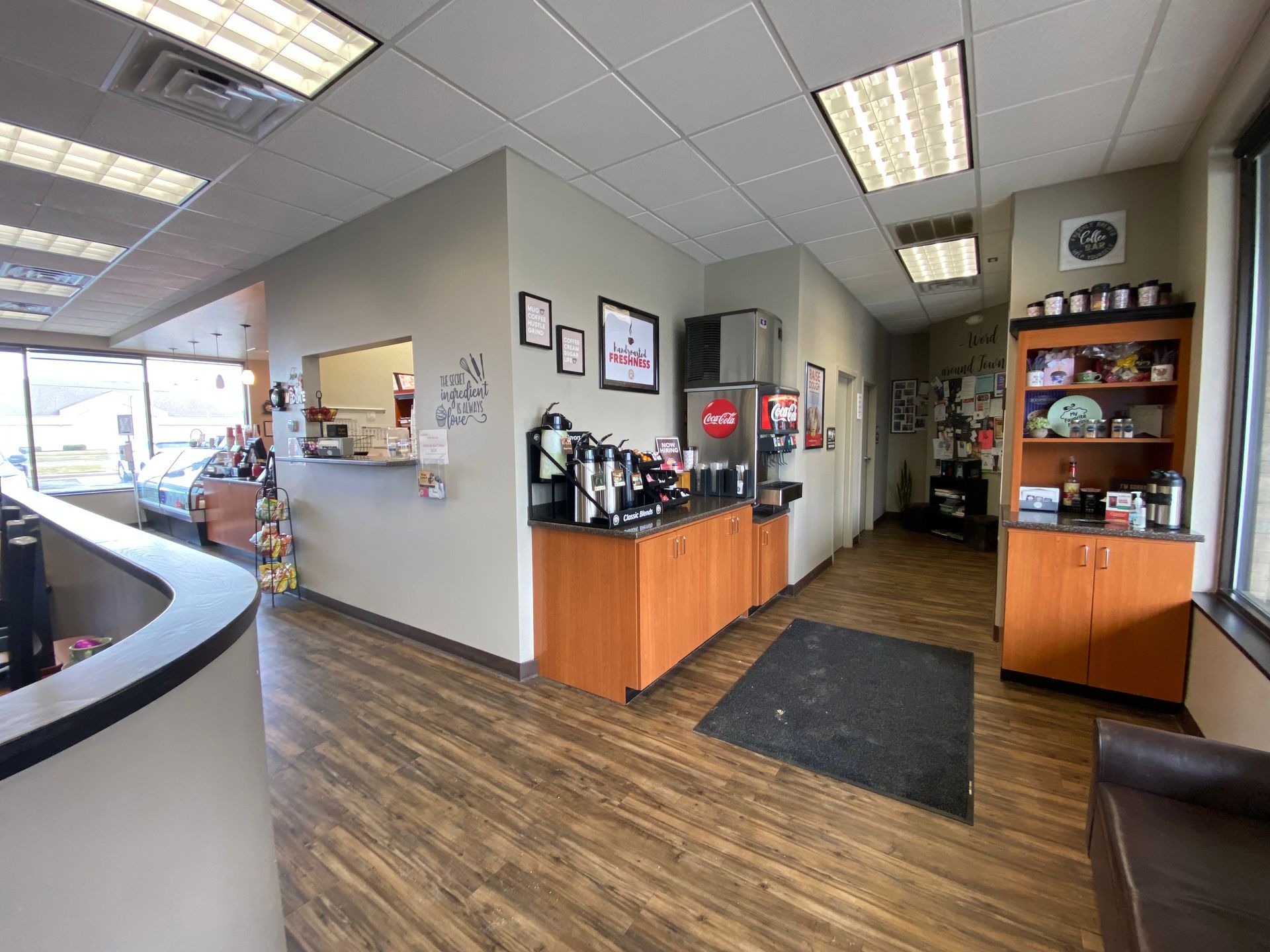 A large room with hardwood floors and a coca cola vending machine.