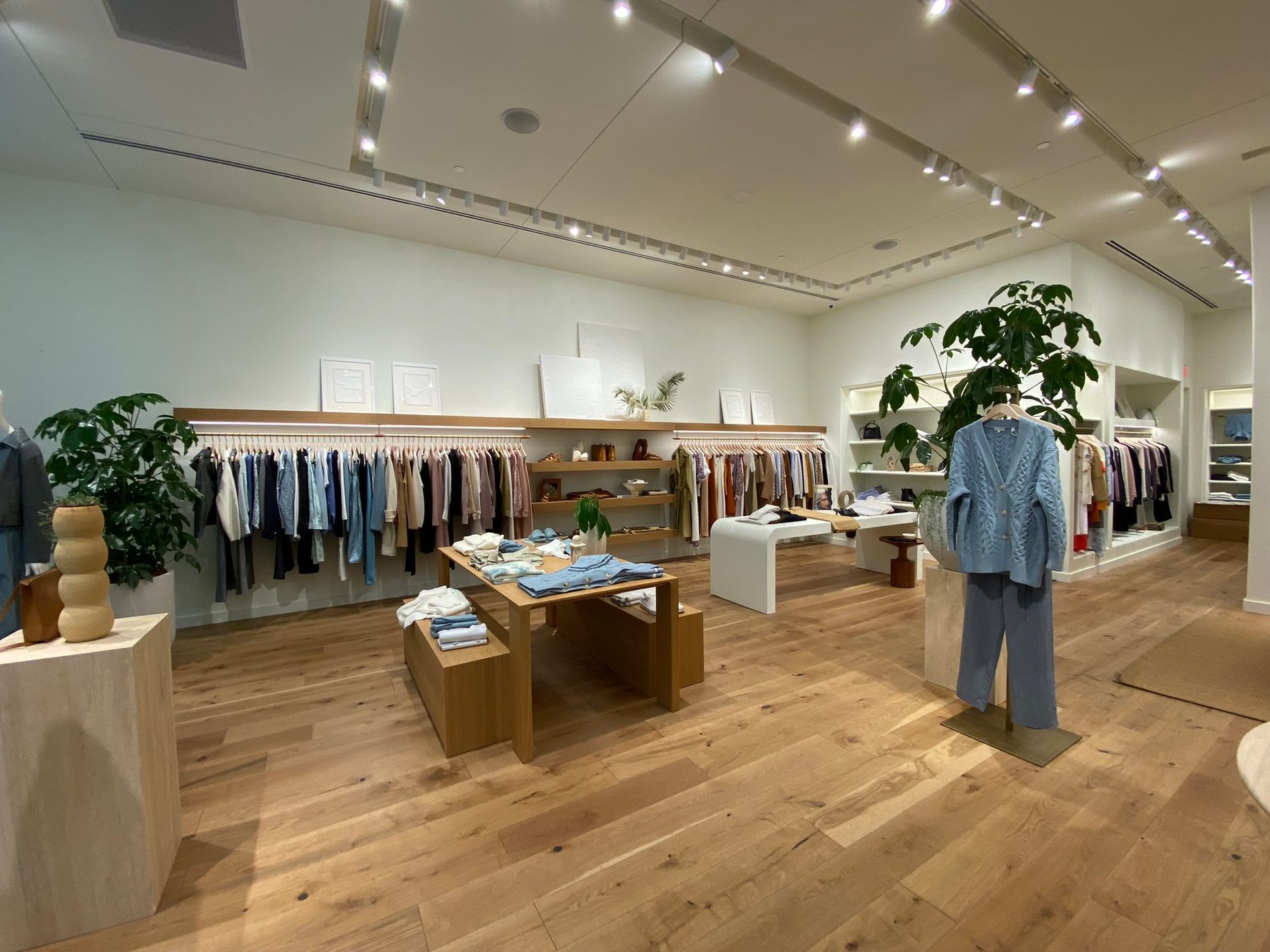 A clothing store with a wooden floor and clothes on display.