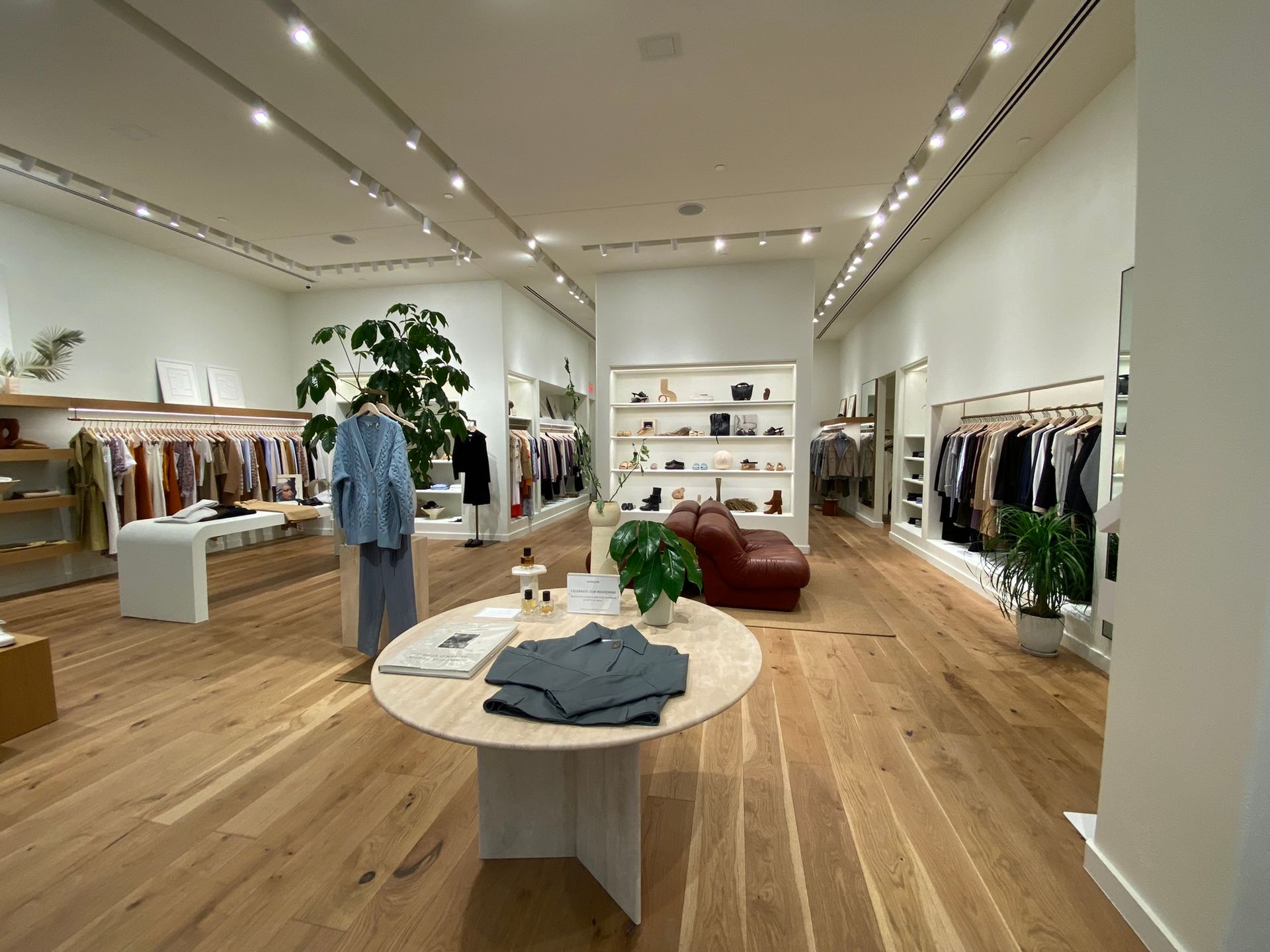 A clothing store with a round table in the middle of the room.