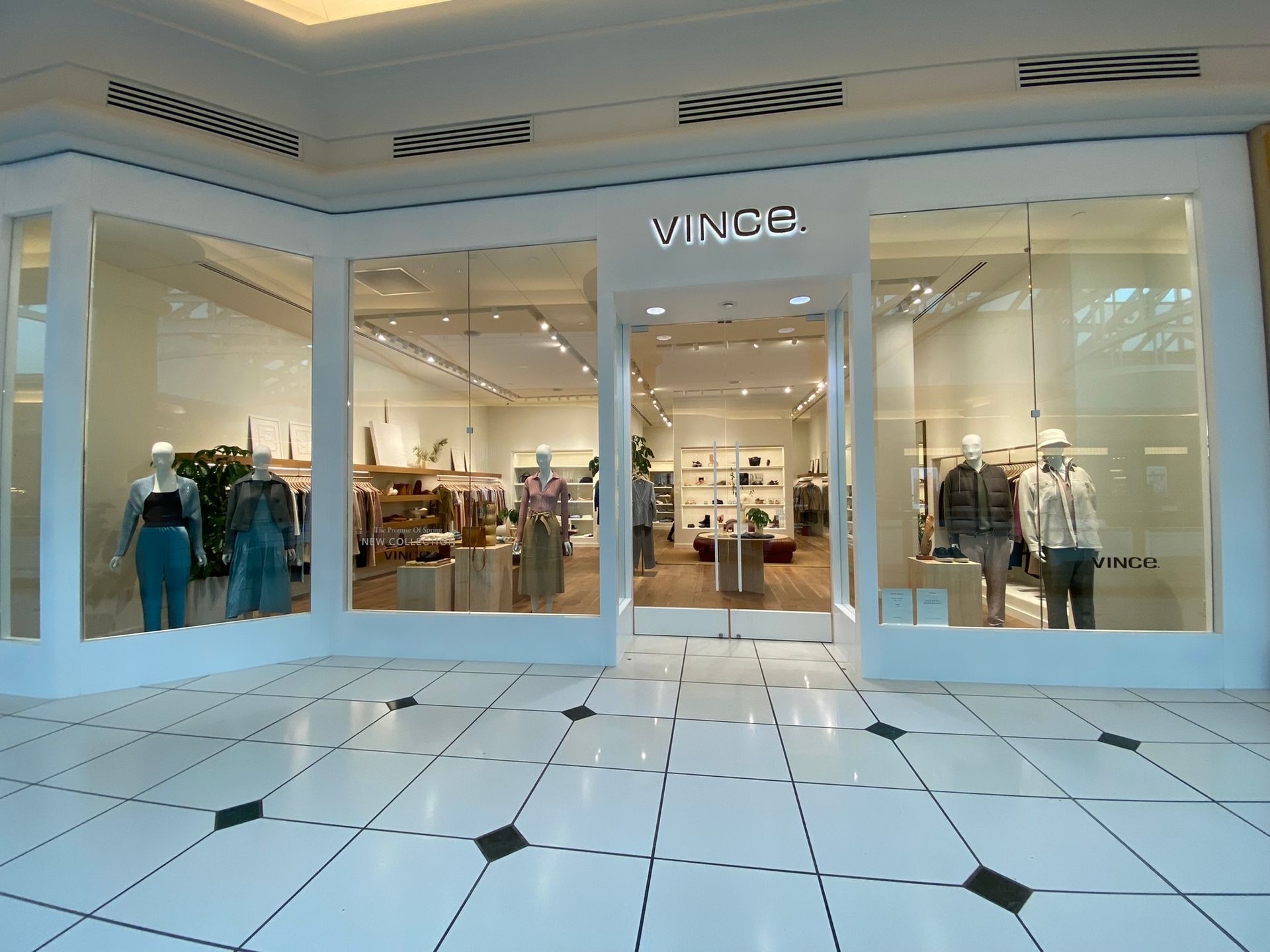 A vince store in a mall with mannequins in the windows