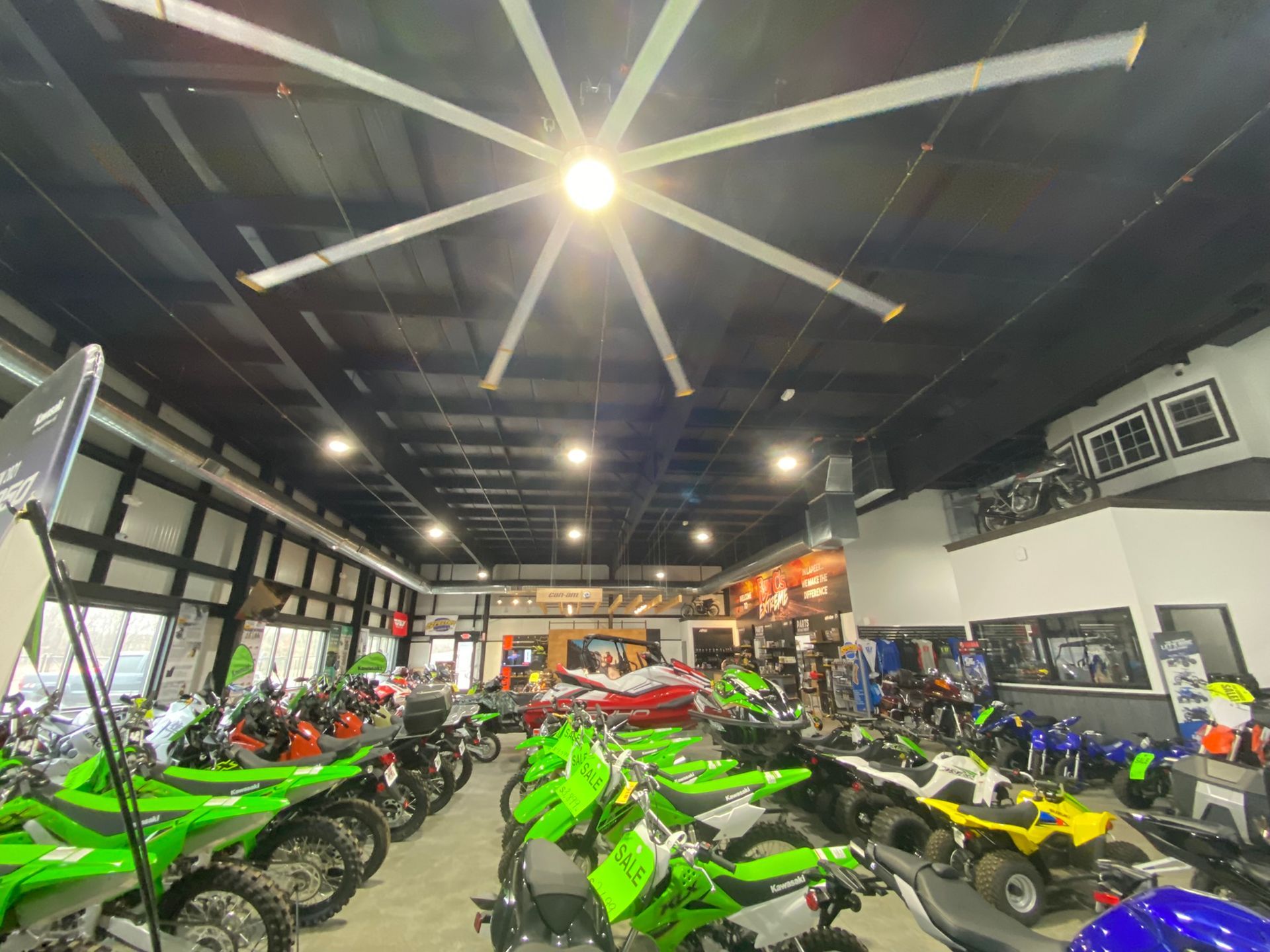 A large ceiling fan is hanging from the ceiling of a motorcycle dealership.