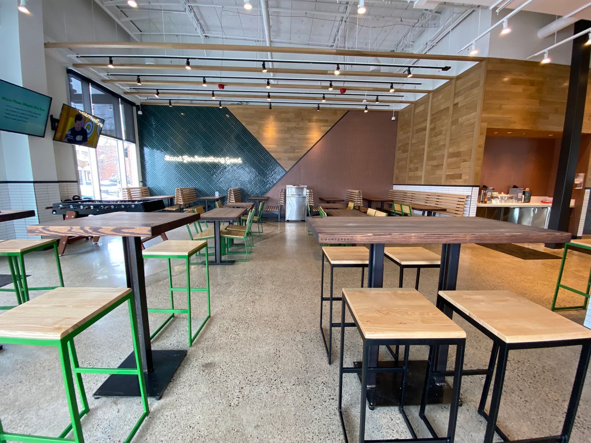 A restaurant with wooden tables and green stools.