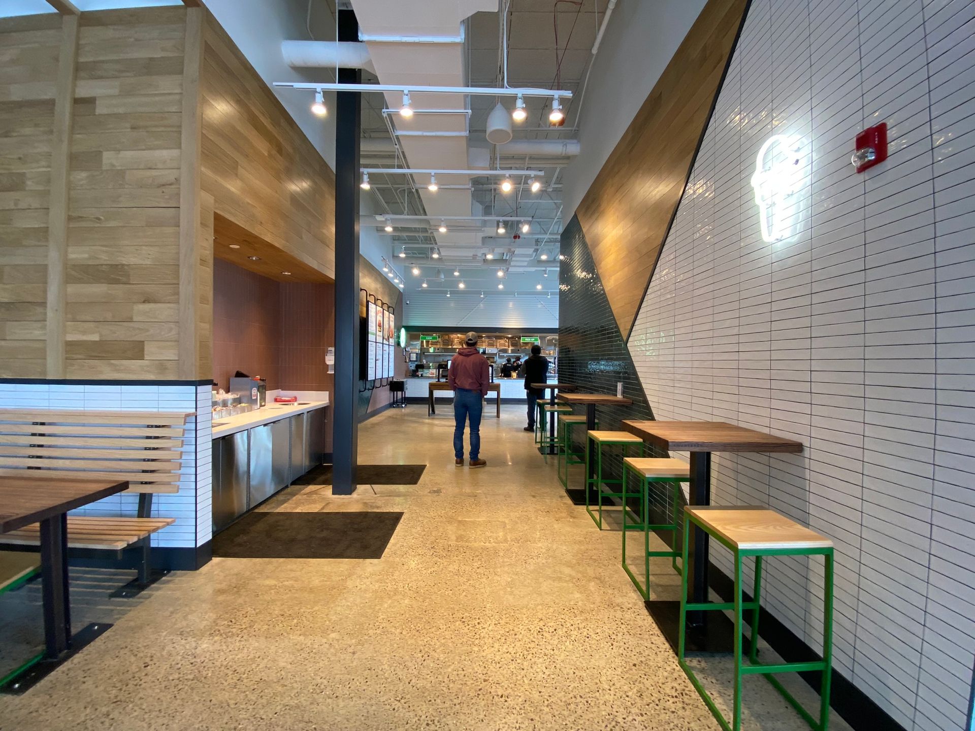 A man is walking down a long hallway in a restaurant.