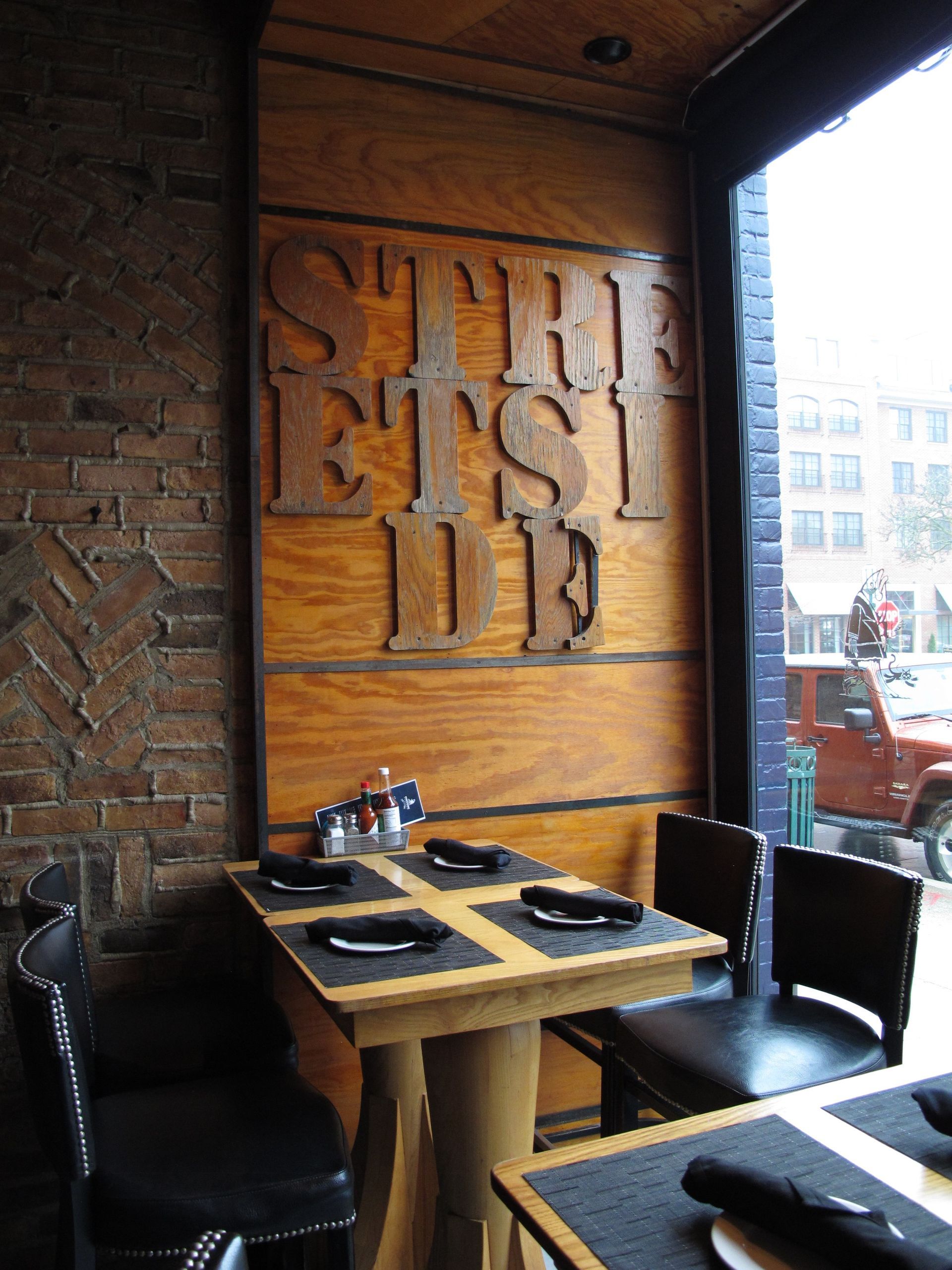 A restaurant with tables and chairs and a sign that says ' steak ' on it