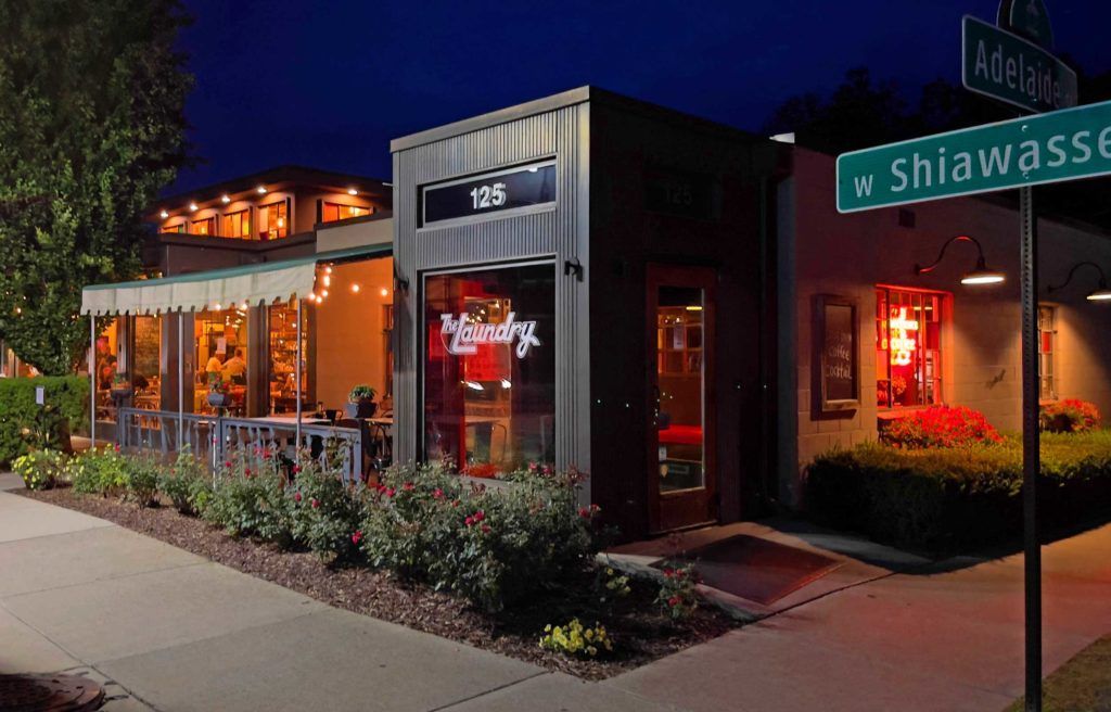 A restaurant is lit up at night with a street sign in front of it.