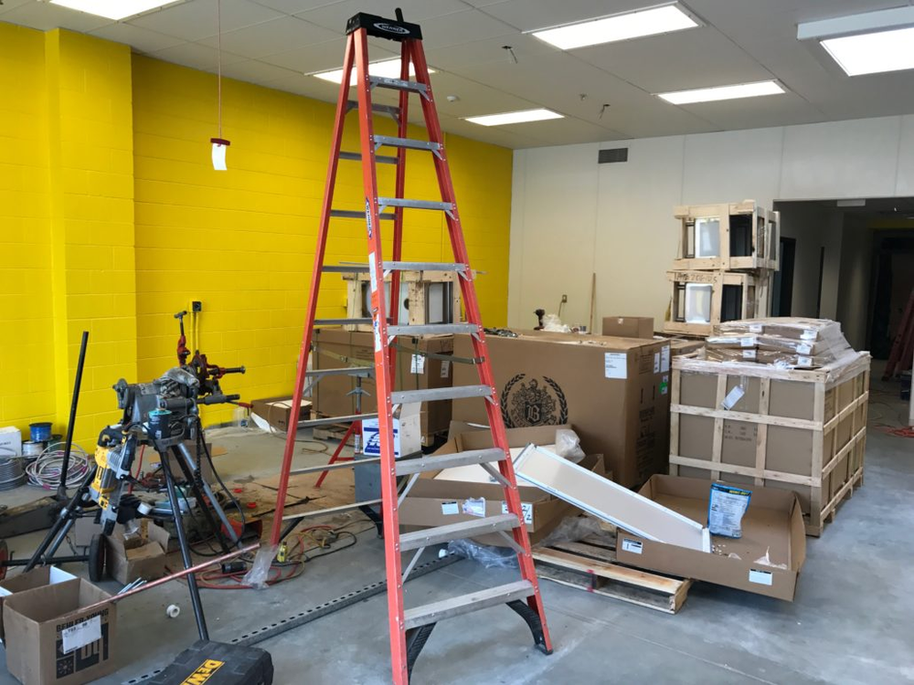 A ladder is sitting in the middle of a room with yellow walls.