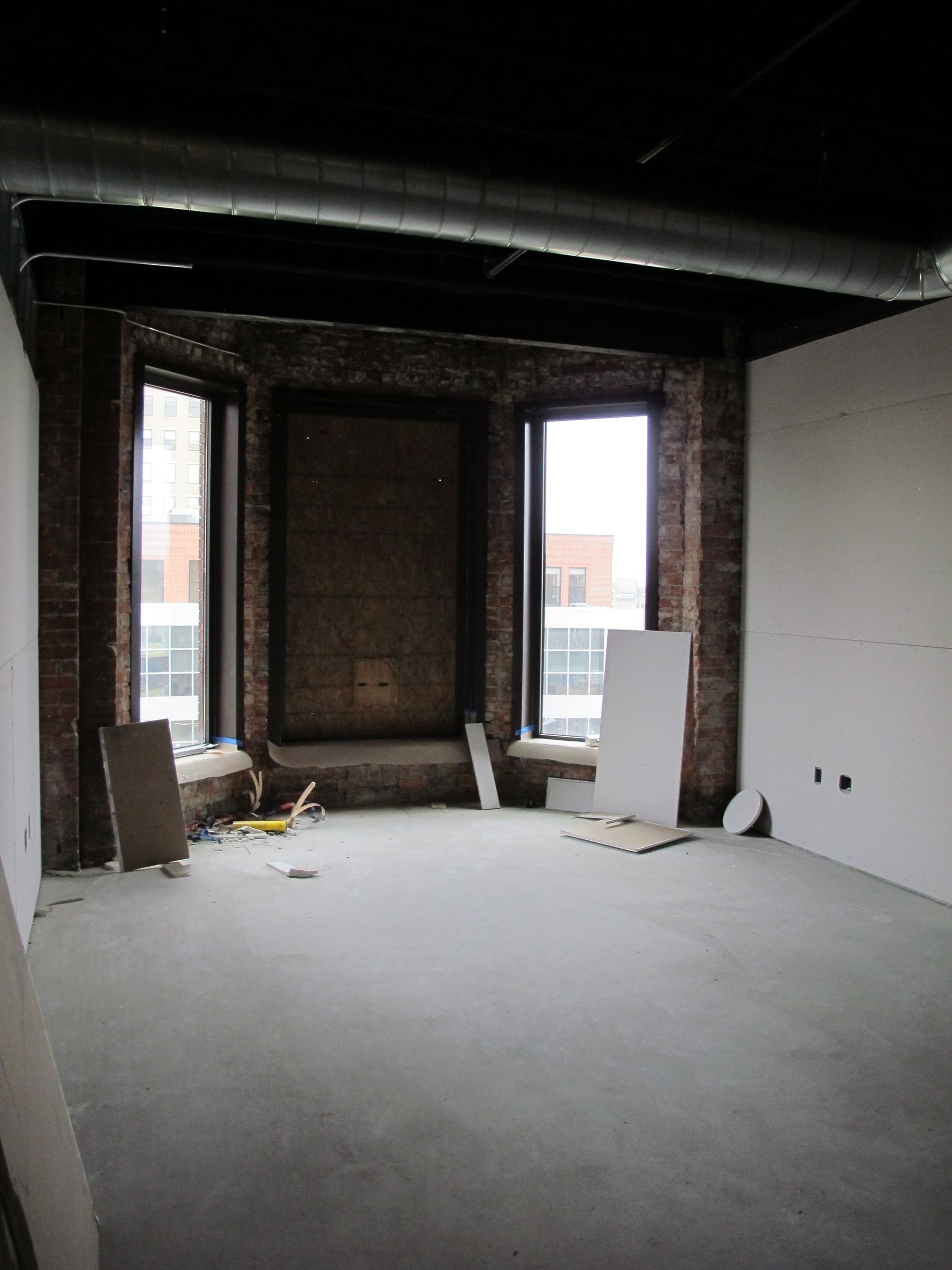 An empty room with a brick wall and a lot of windows