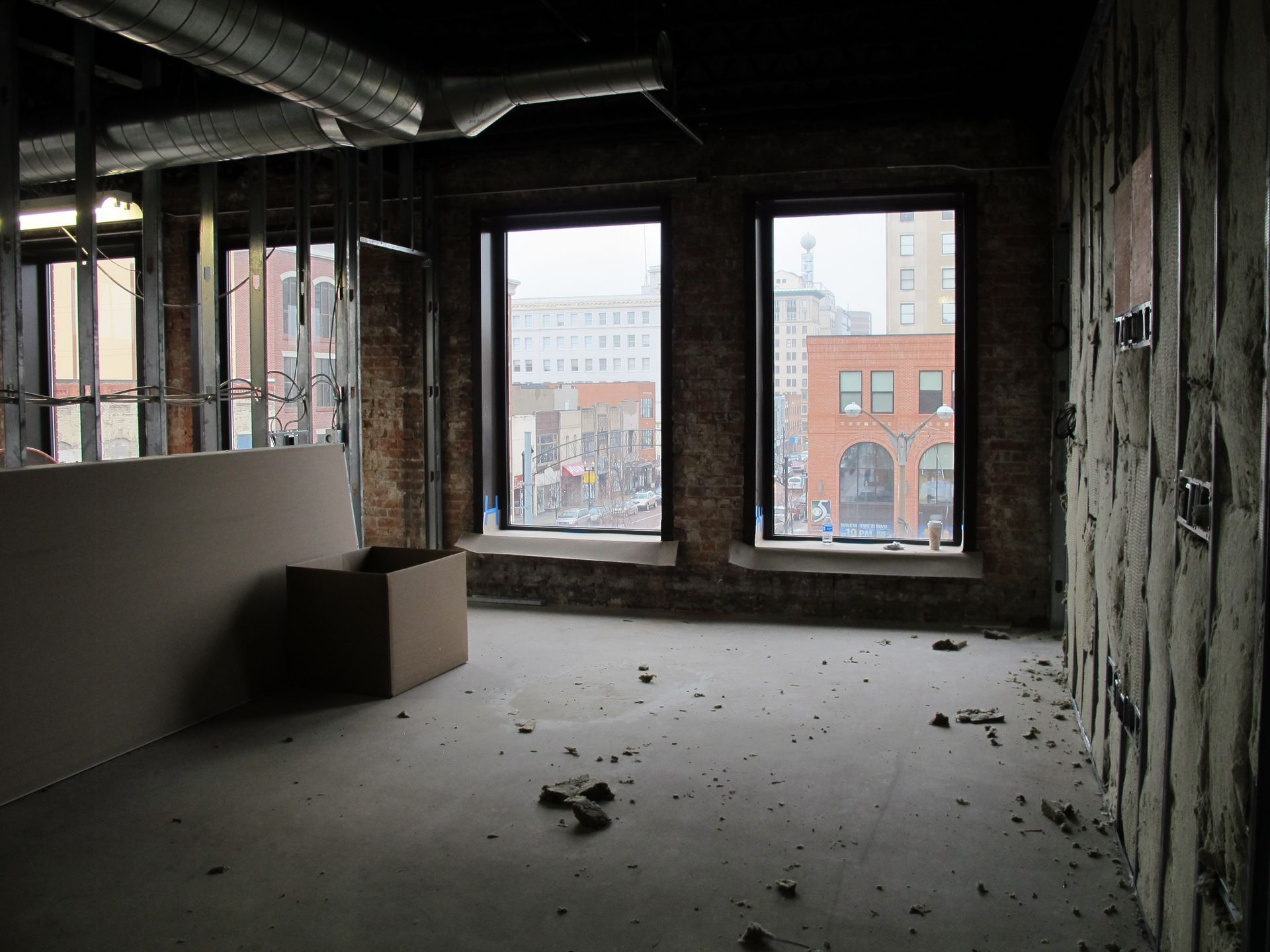 An empty room with two windows and a brick wall