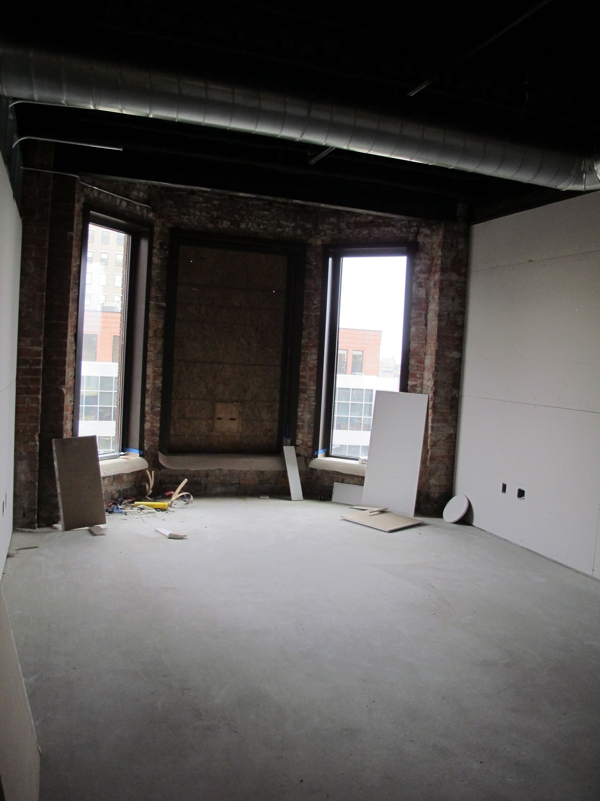 An empty room with a brick wall and a lot of windows