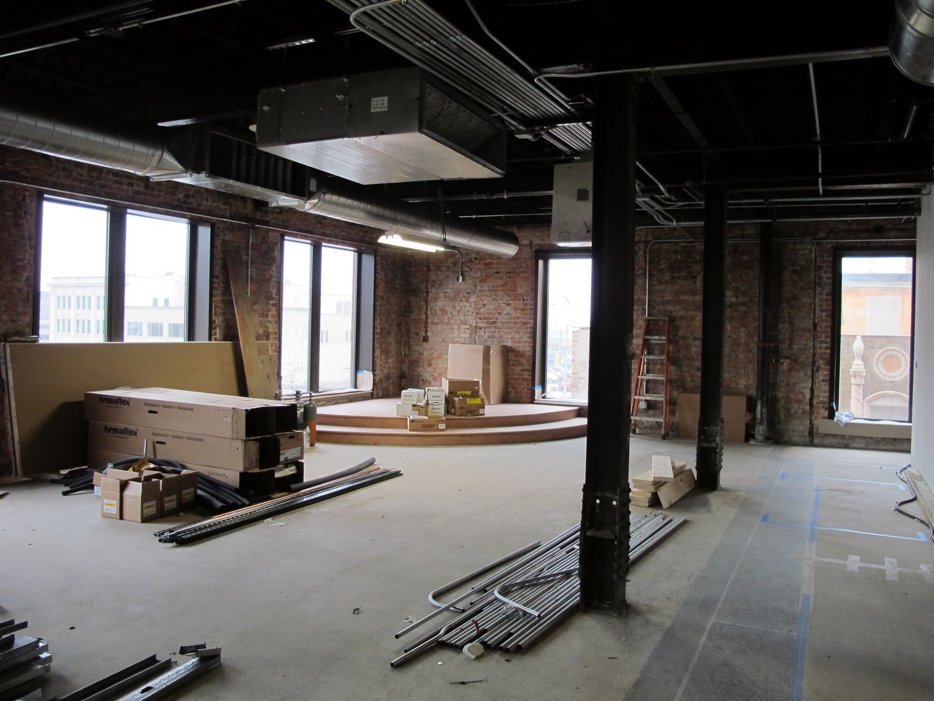 A large empty room with a brick wall and a lot of windows