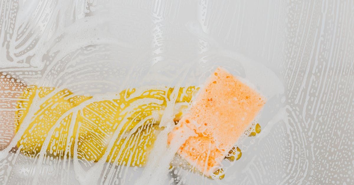 A sponge is being used to clean a window with soap and water.