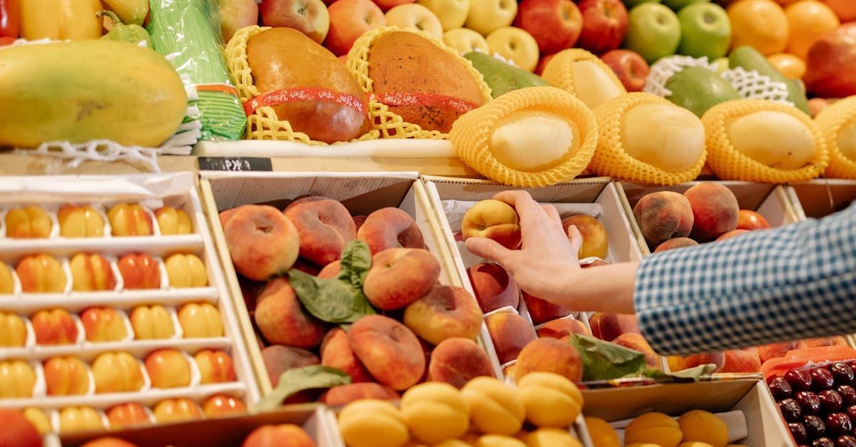 A person is picking a pear from a box of fruit.