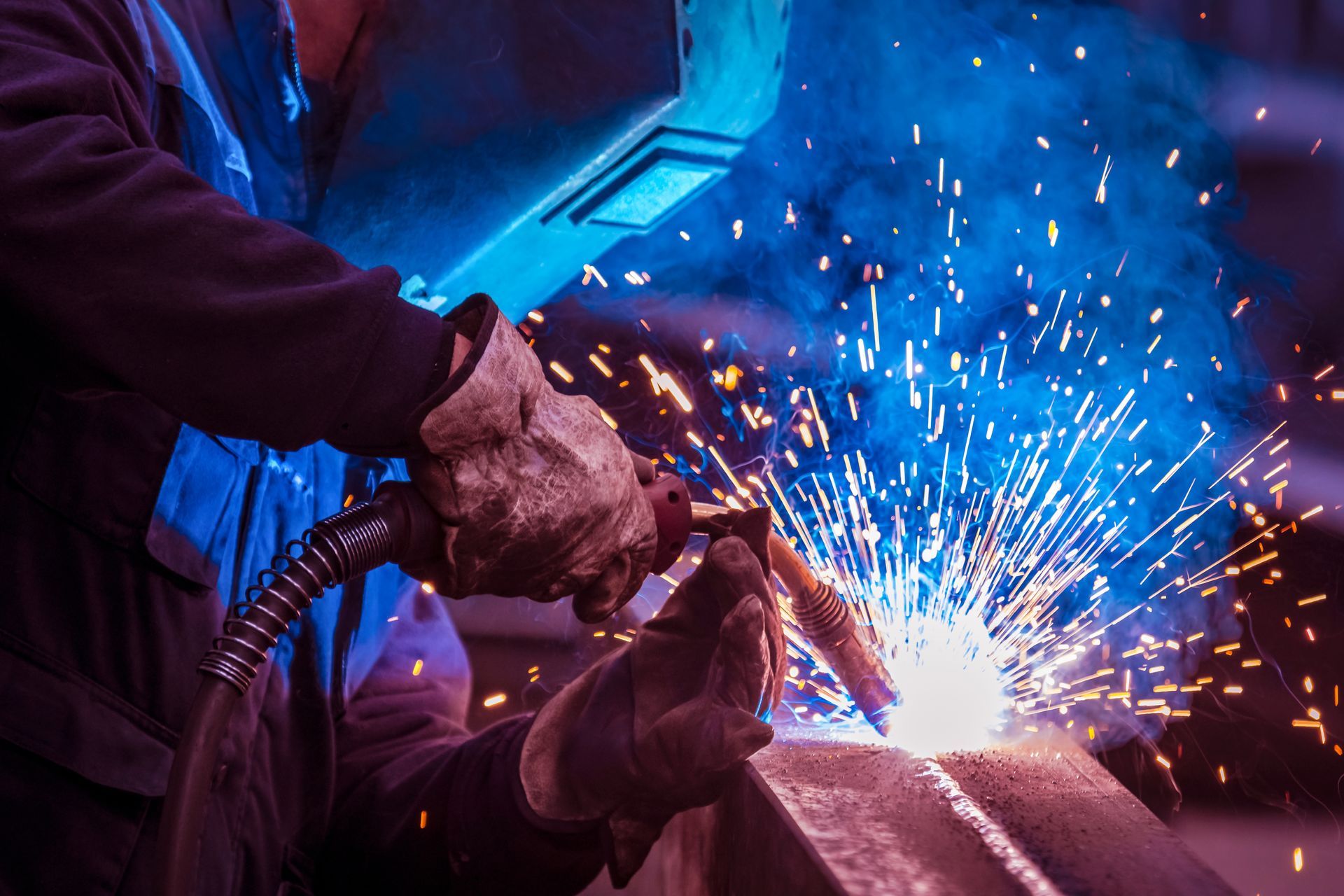 Man with face and eye protection shield welding steel girder Man with face and eye protection shield welding steel girder