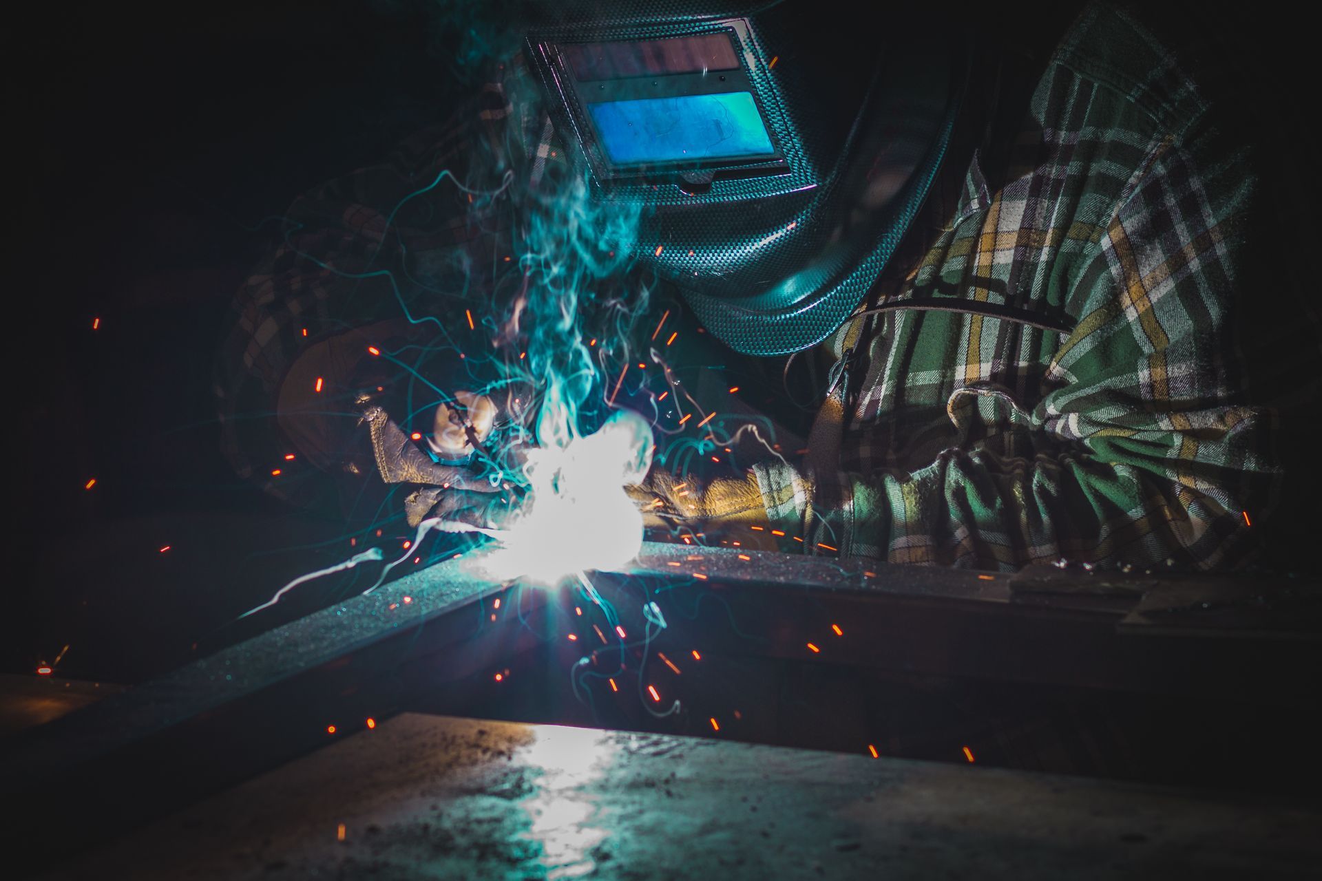 Bright sparks flying as a welder works on metal in a dim workshop. Bright sparks flying as a welder works on metal in a dim workshop.