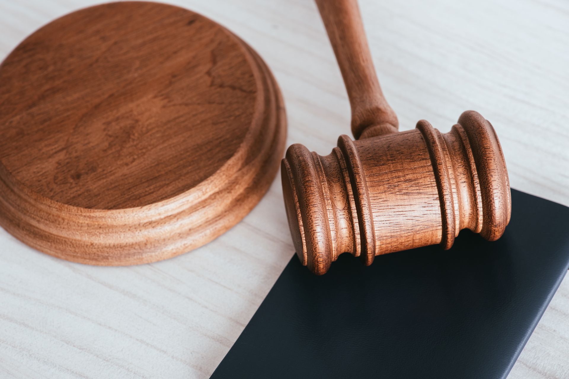 A wooden judge 's gavel is sitting on top of a black book.