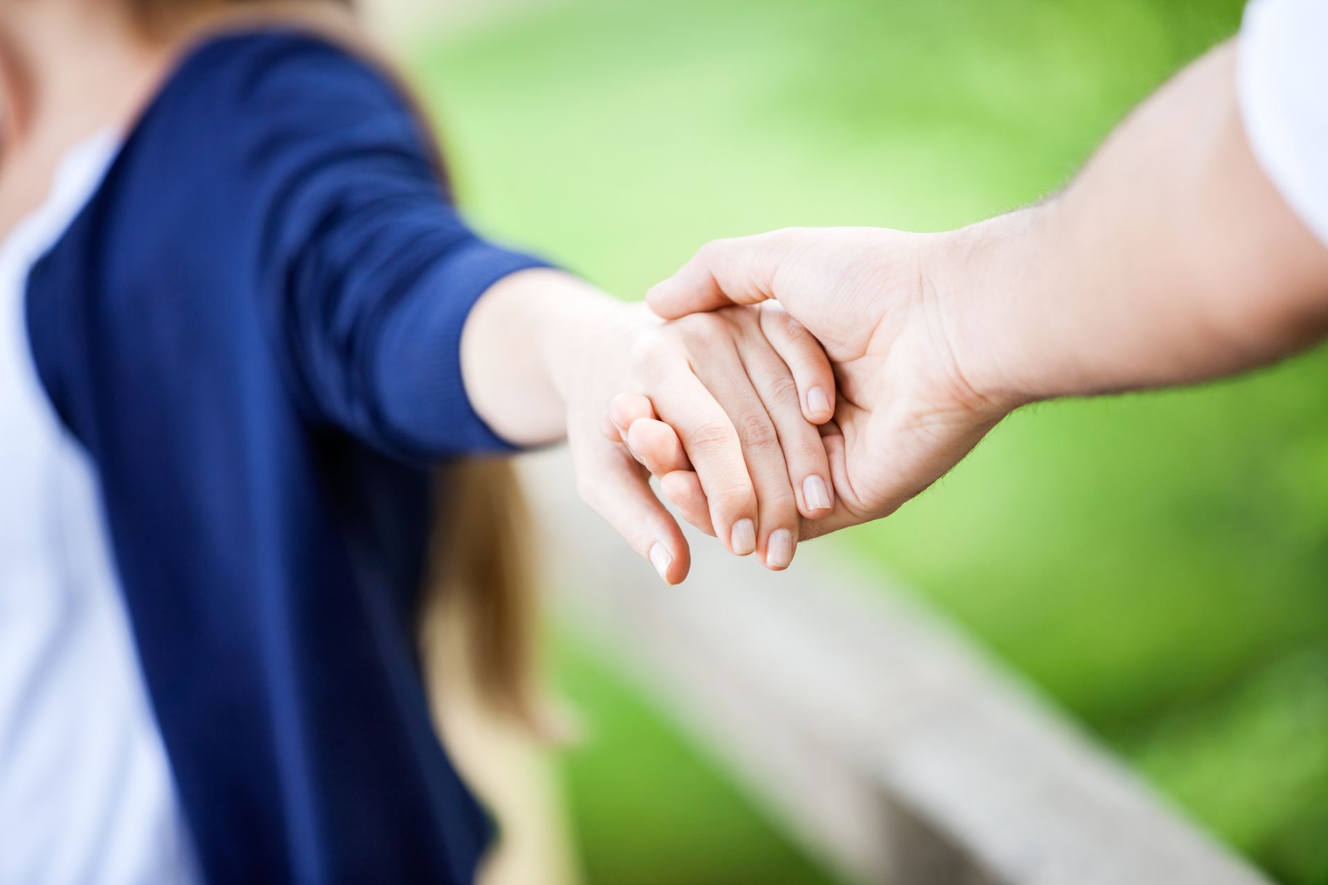 A man and a woman are holding hands on a wooden bridge.