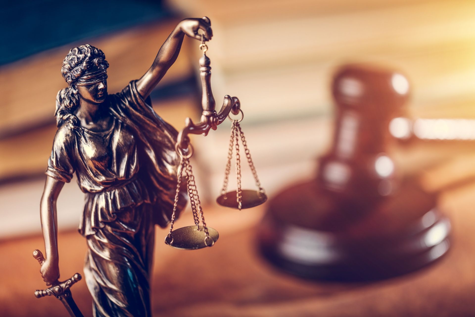 Lady Justice on the left side facing the right with a gavel in the foreground atop a desk. 