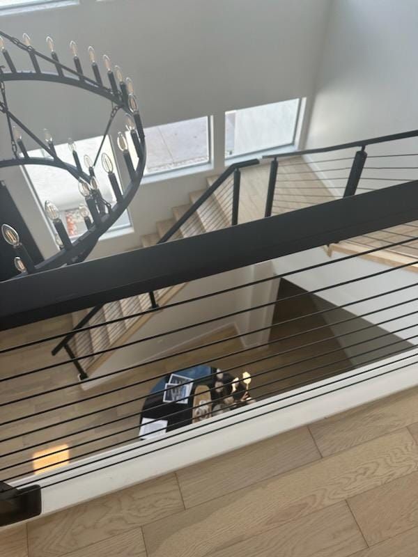 Modern staircase with black railing and chandelier, view from above.