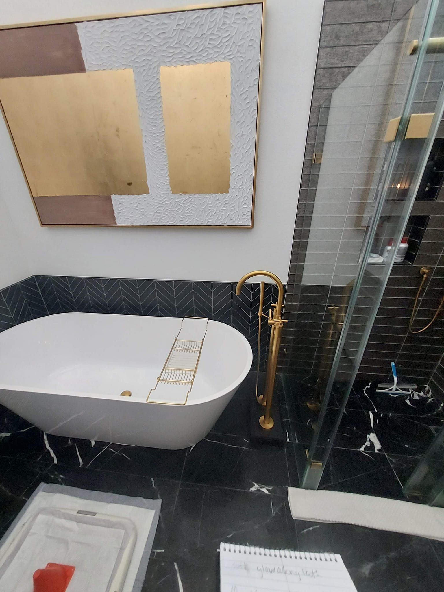 Luxury bathroom with a gold faucet, white tub, and black marble flooring.