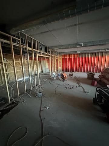 Interior construction site, wooden frame walls, exposed wiring, concrete floor.