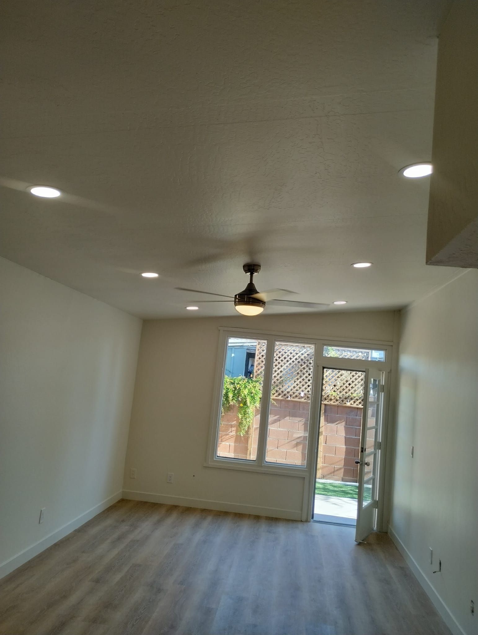 Empty room with ceiling lights, a ceiling fan, and a door leading outside.