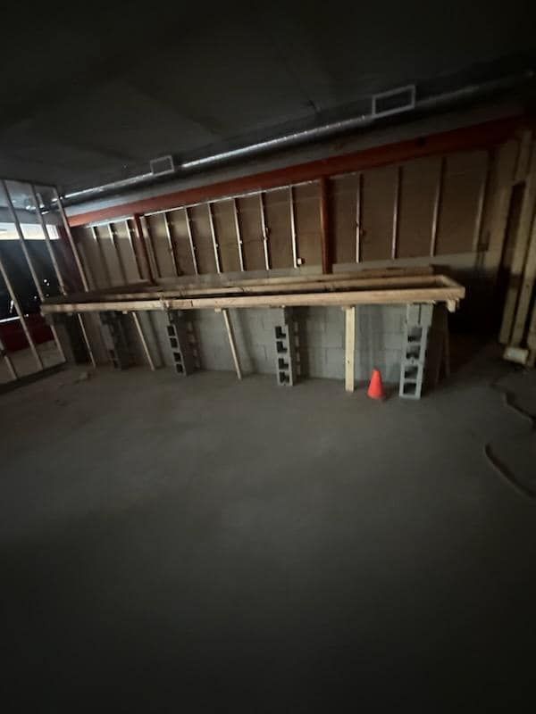 Construction site: a long wooden table supported by cinder blocks, with a partially framed wall and a safety cone.