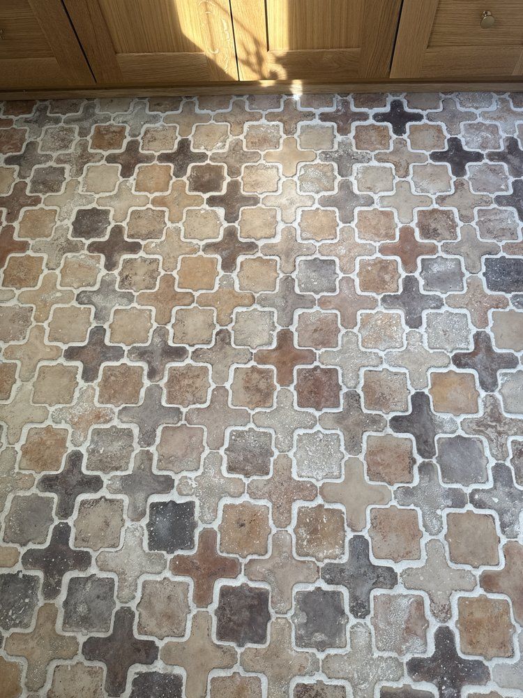 Floor with repeating cross-shaped tile pattern in shades of brown, tan, and gray.