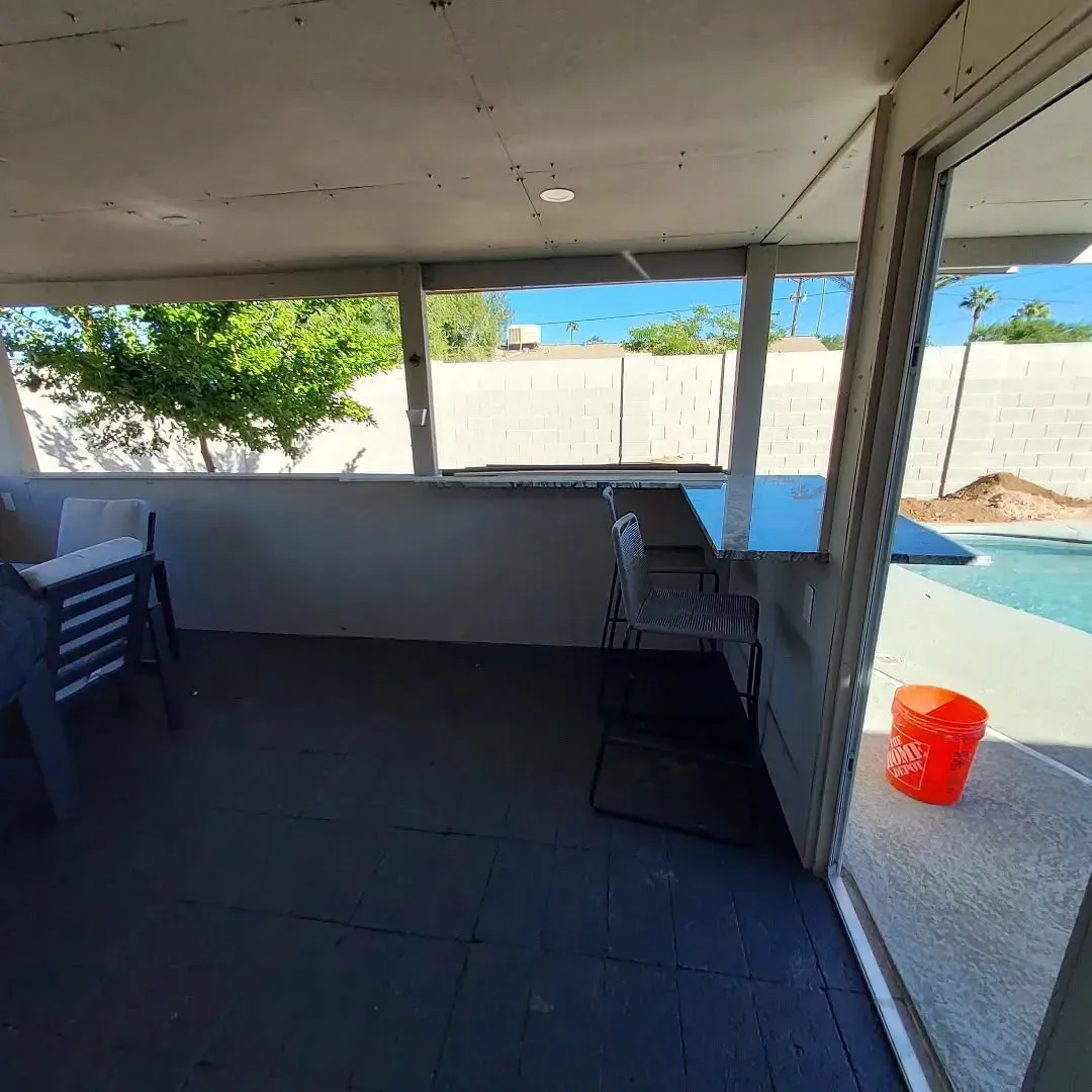 Covered patio with bar, pool access, chairs, and a bright orange bucket.