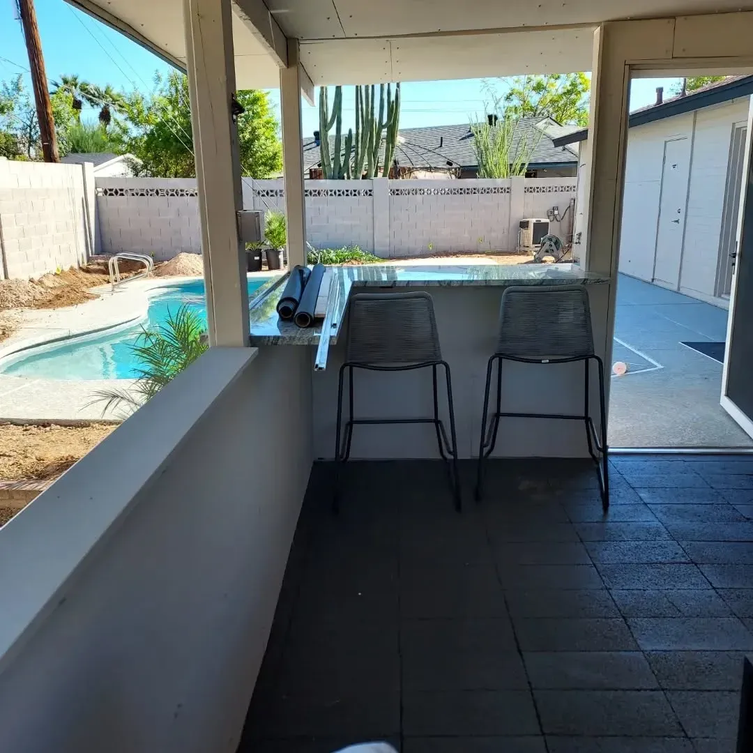 Covered patio with bar seating, pool, and backyard view.