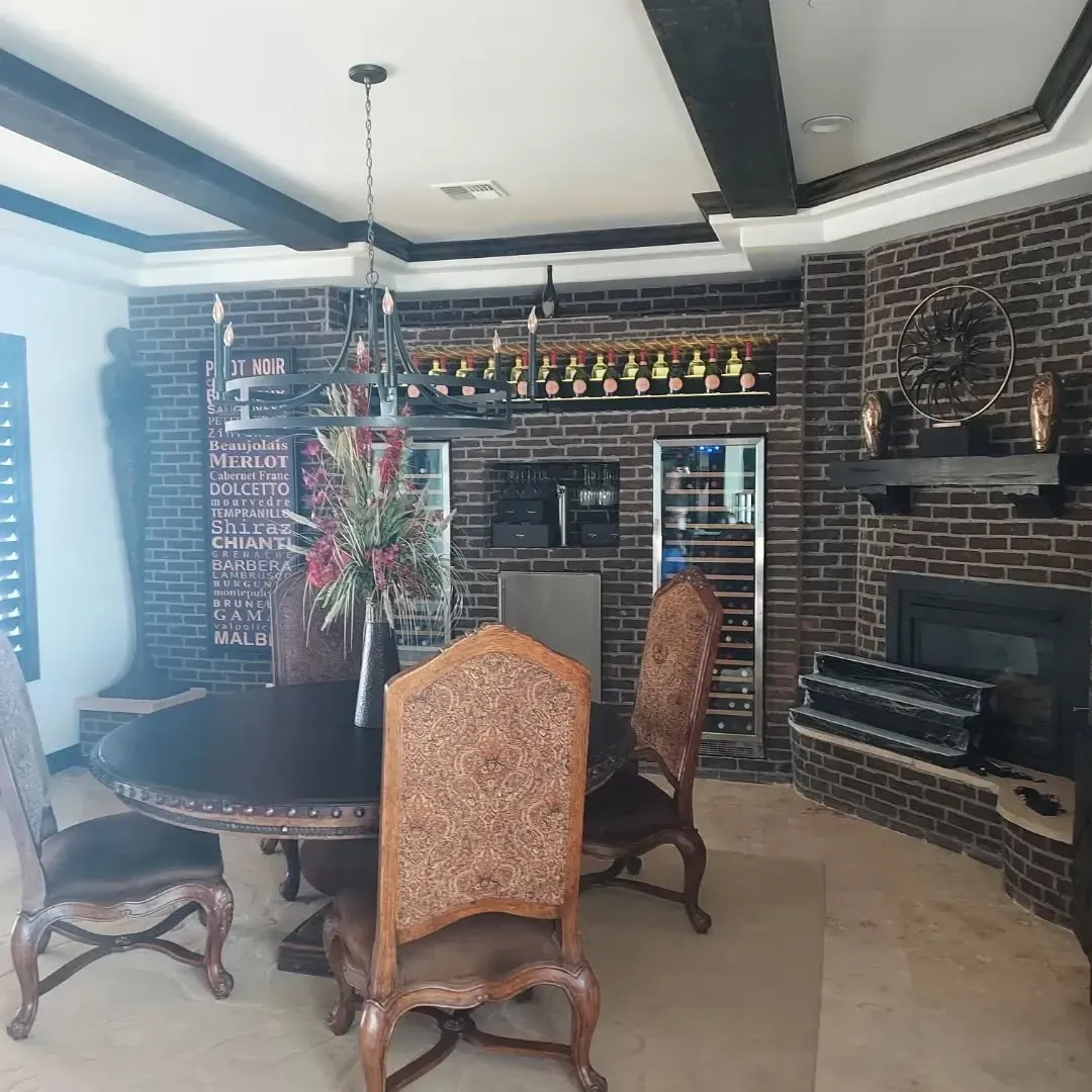 Formal dining room with a brick wall, a fireplace, a wine rack, and a round table with chairs.