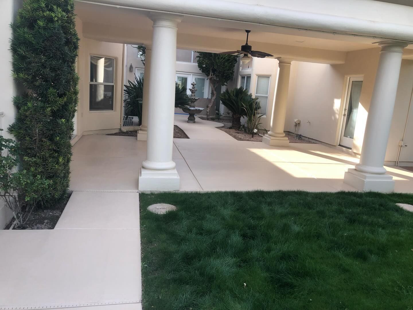 Covered patio with white columns, a grassy area, and pathway.