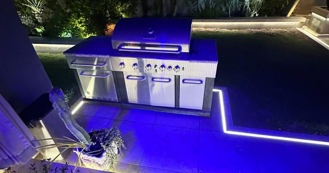 Outdoor grill with stainless steel doors and blue accent lighting.