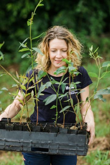 A woman is holding a tray of plants in her hands.