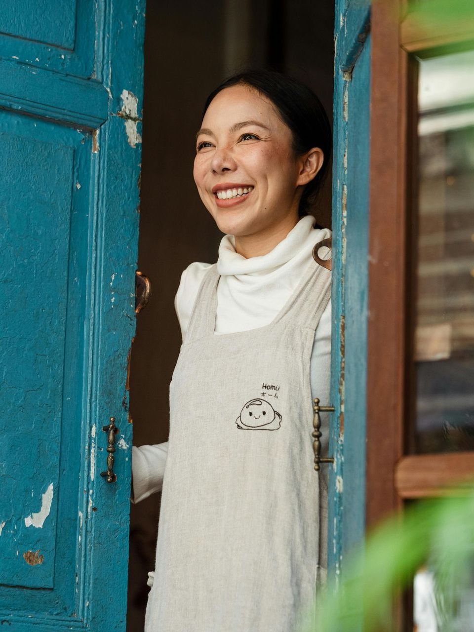A woman is smiling while standing in a doorway.
