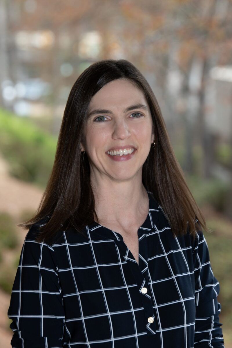 A woman in a plaid shirt is smiling for the camera.