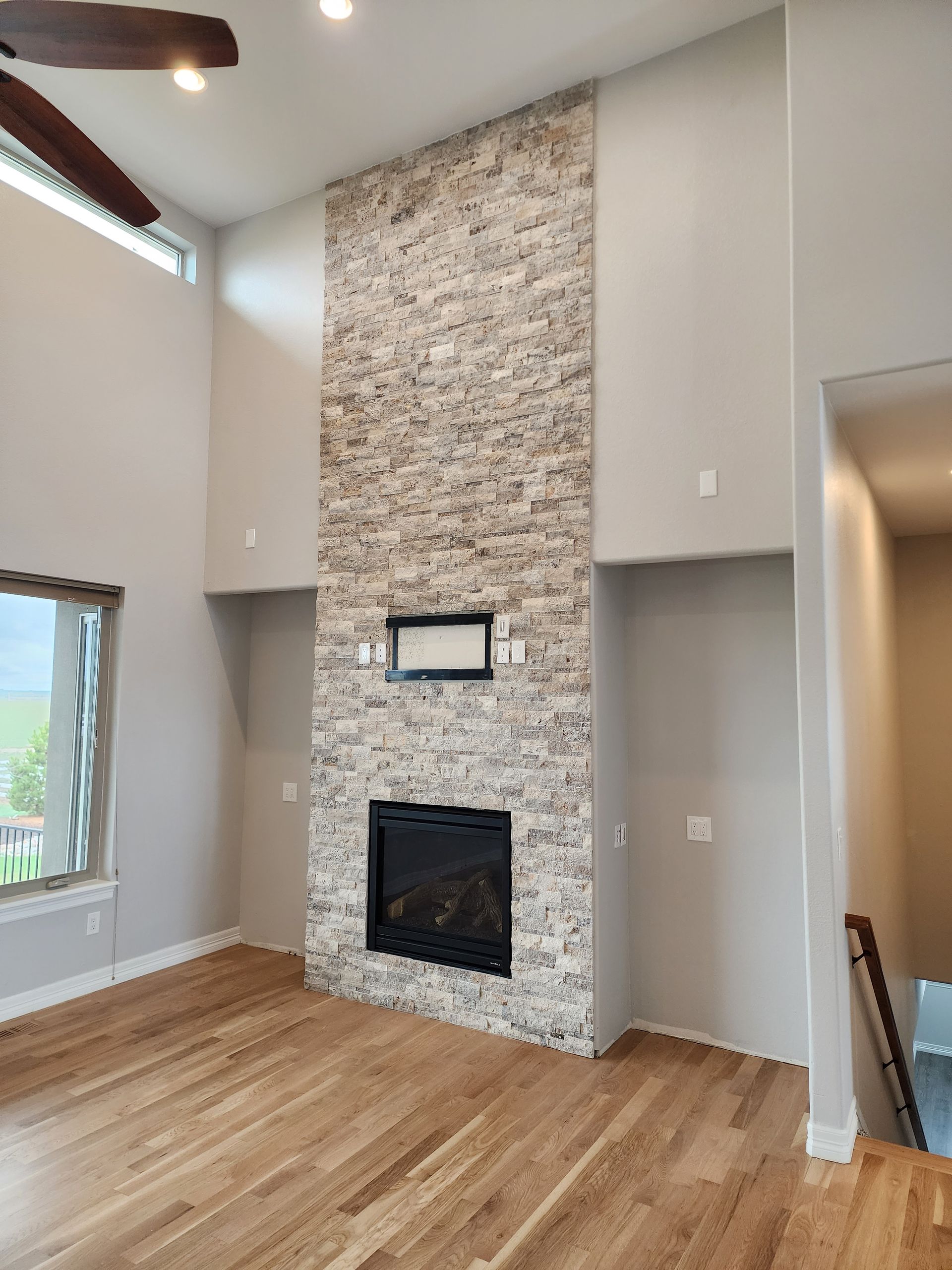 Fireplace with stone surround in a room with light wood floors and gray walls.