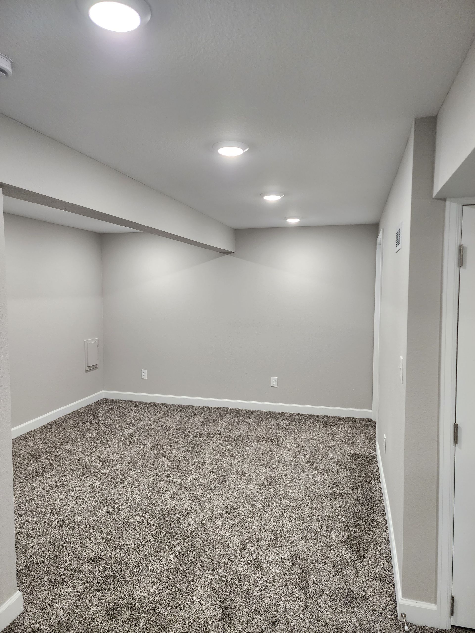 Empty room with gray walls, carpet, and recessed lights; doorway on the right.
