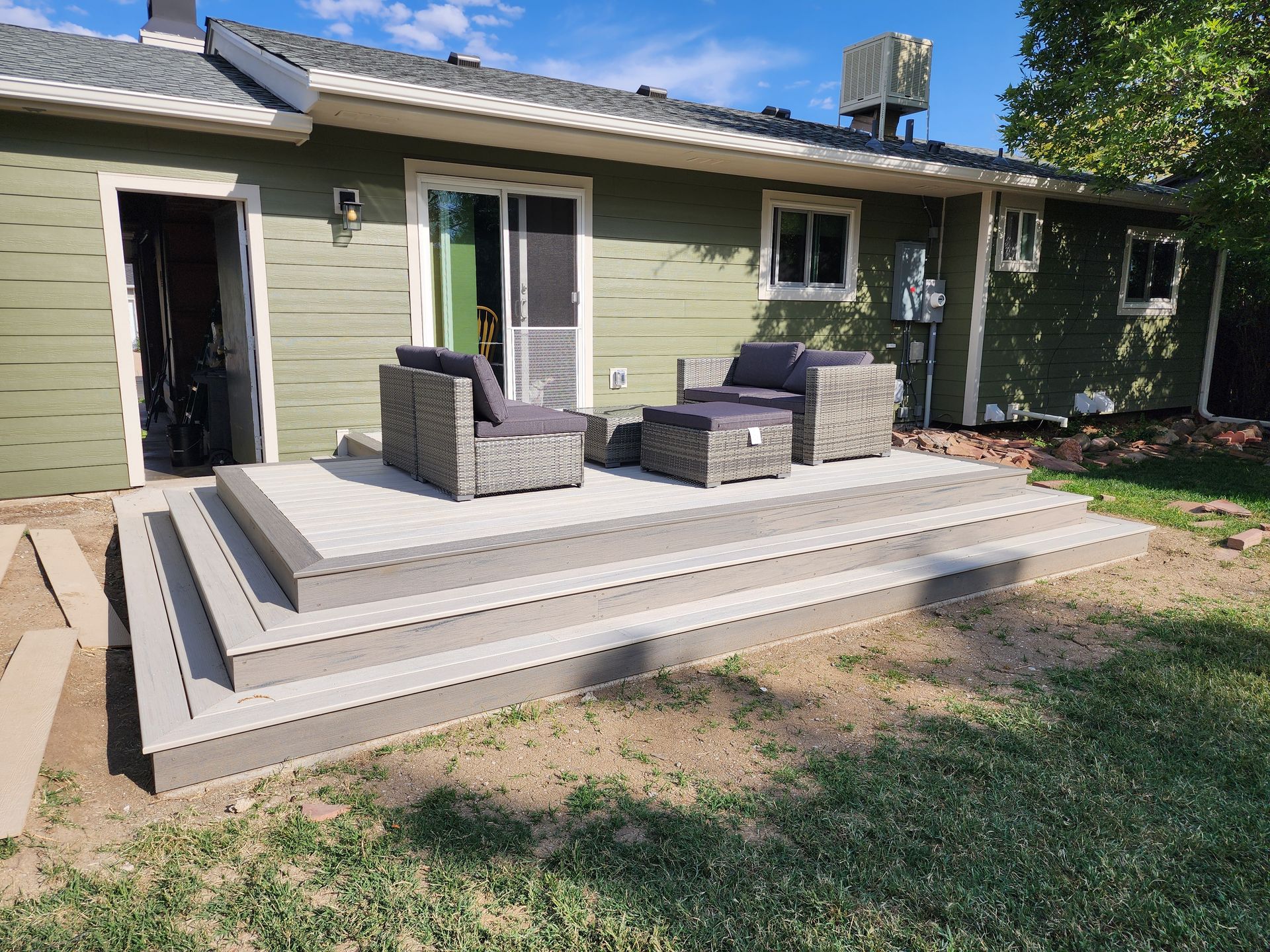 A newly built gray composite deck with outdoor furniture in a backyard.