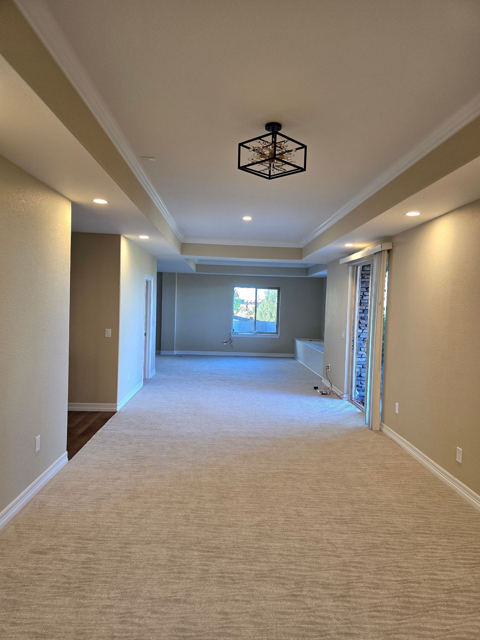Spacious room with beige carpet, recessed lighting, and a decorative ceiling fixture.
