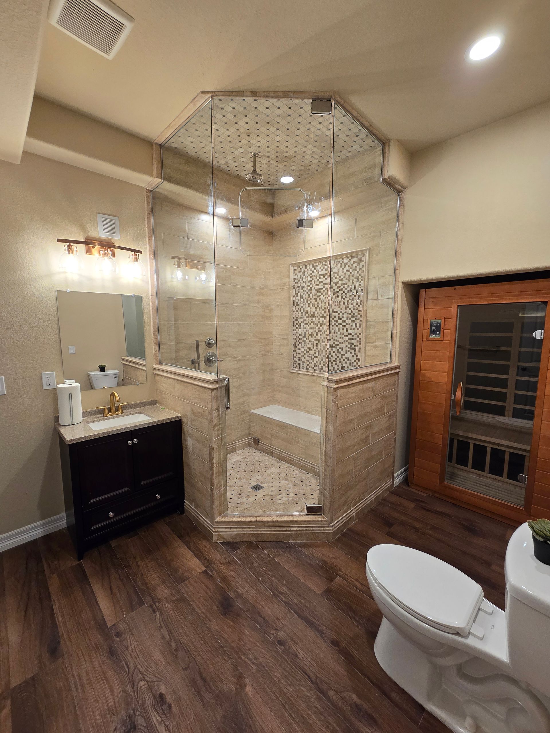 Spacious bathroom with glass shower, dark wood floor, and sauna.