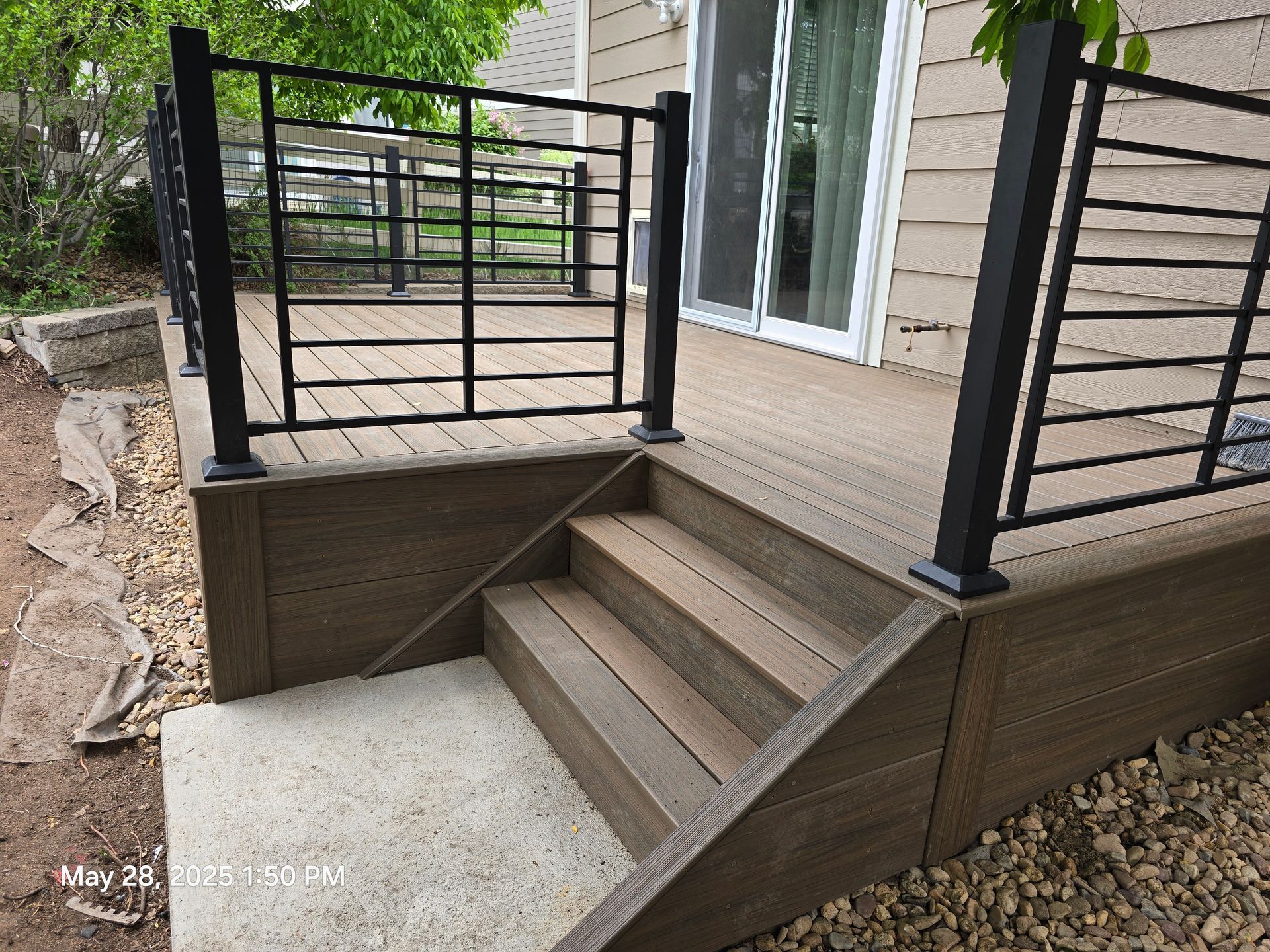 Composite deck with stairs and black metal railing.