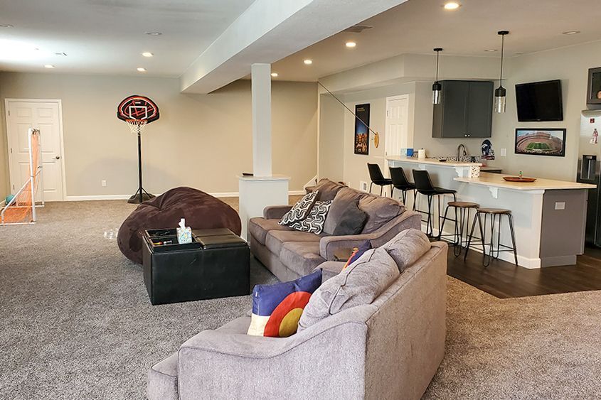Spacious finished basement with a basketball hoop, seating area, and a kitchen with a bar.