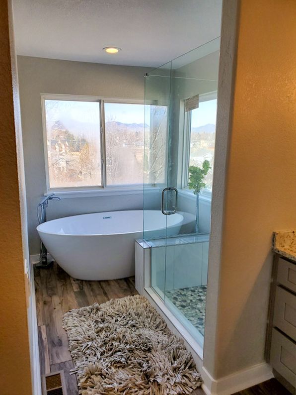 Modern bathroom with a white tub near a window and a glass shower.