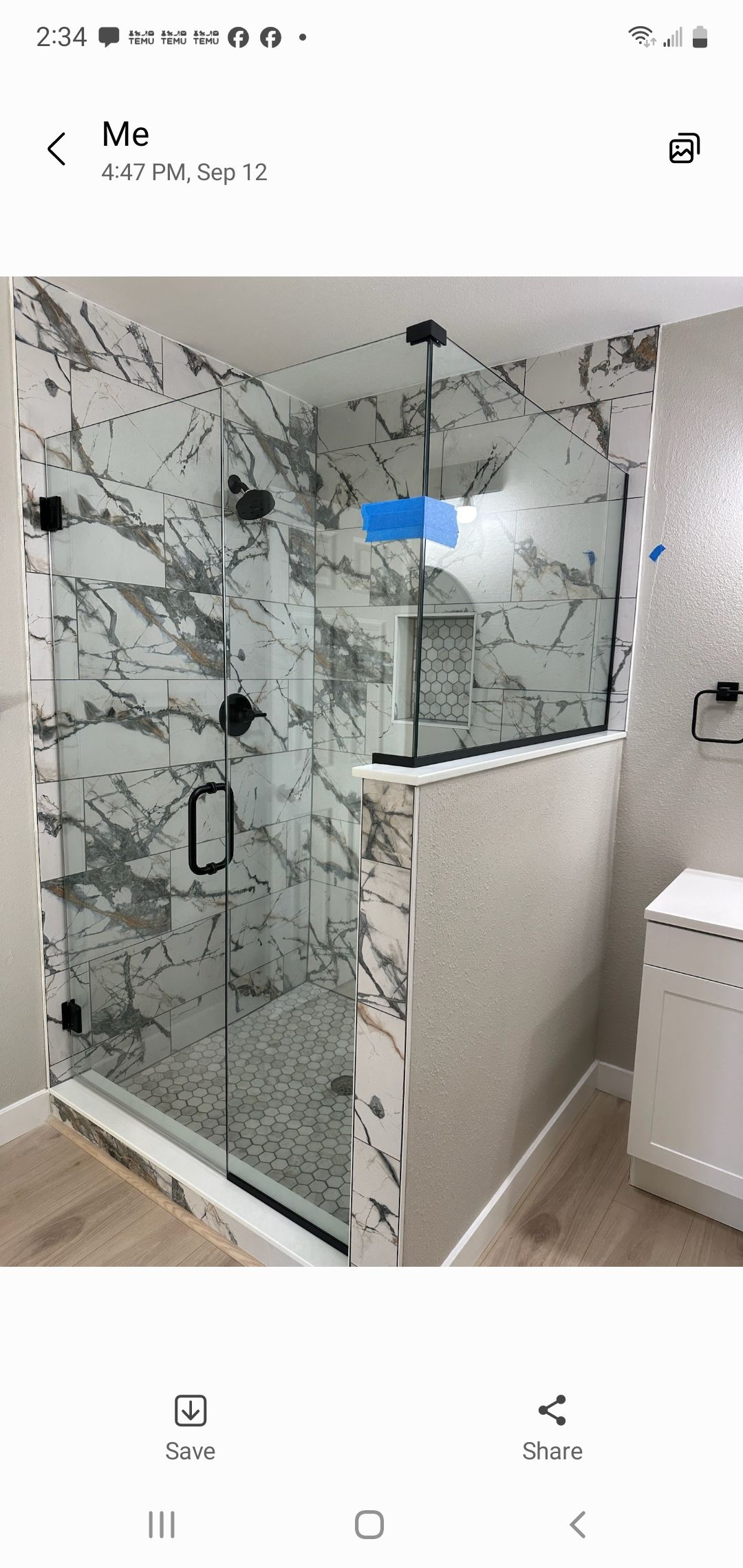 Modern bathroom with a glass shower door and marble tile walls.