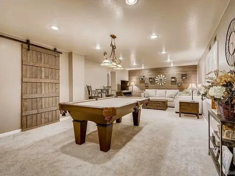Spacious recreation room with pool table, seating area, and rustic wooden accents.