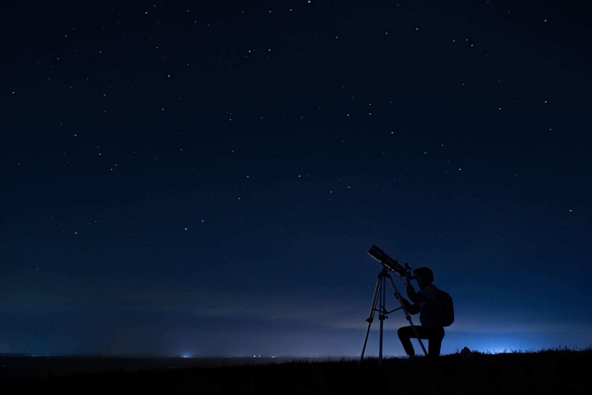 A man is looking through a telescope at the night sky.