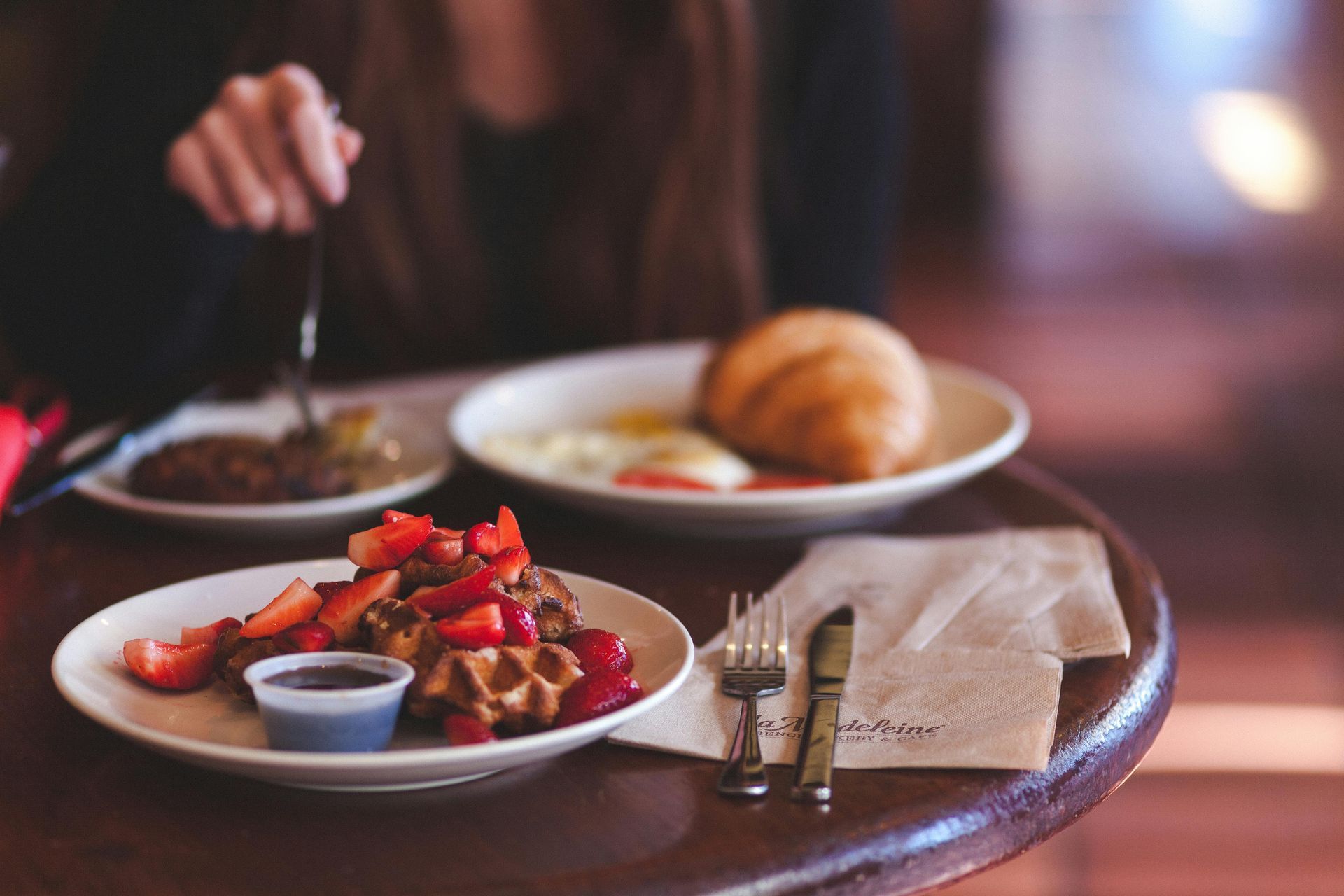 A person is sitting at a table eating a plate of food.