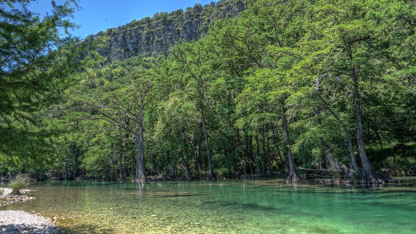 A lake surrounded by trees and mountains with a mountain in the background.