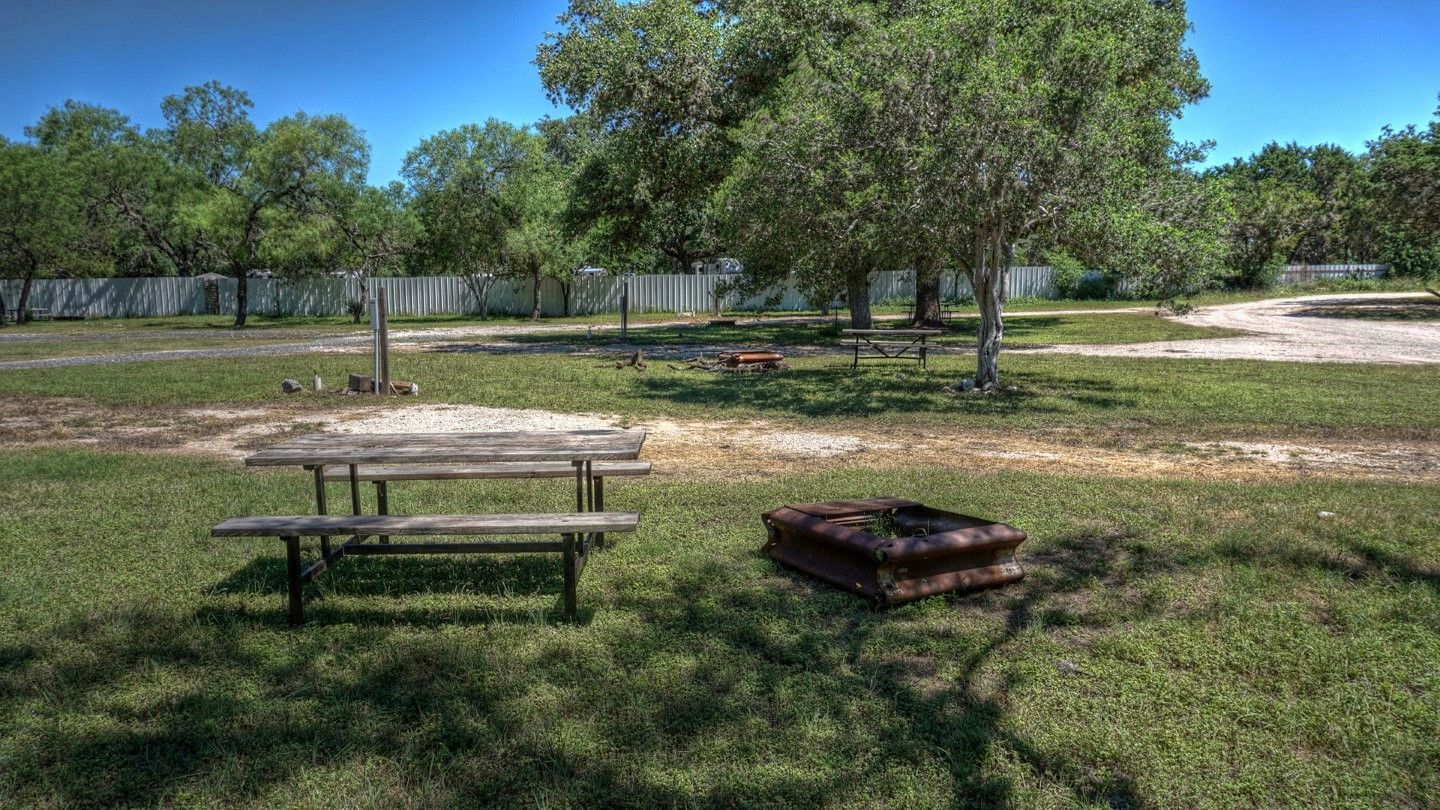 There is a picnic table and a fire pit in the grass.
