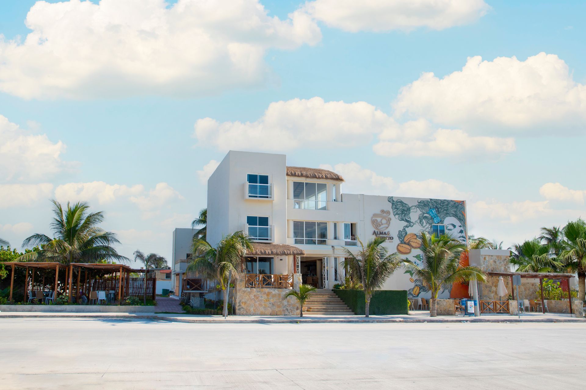 Un gran edificio blanco con muchas ventanas está rodeado de palmeras.